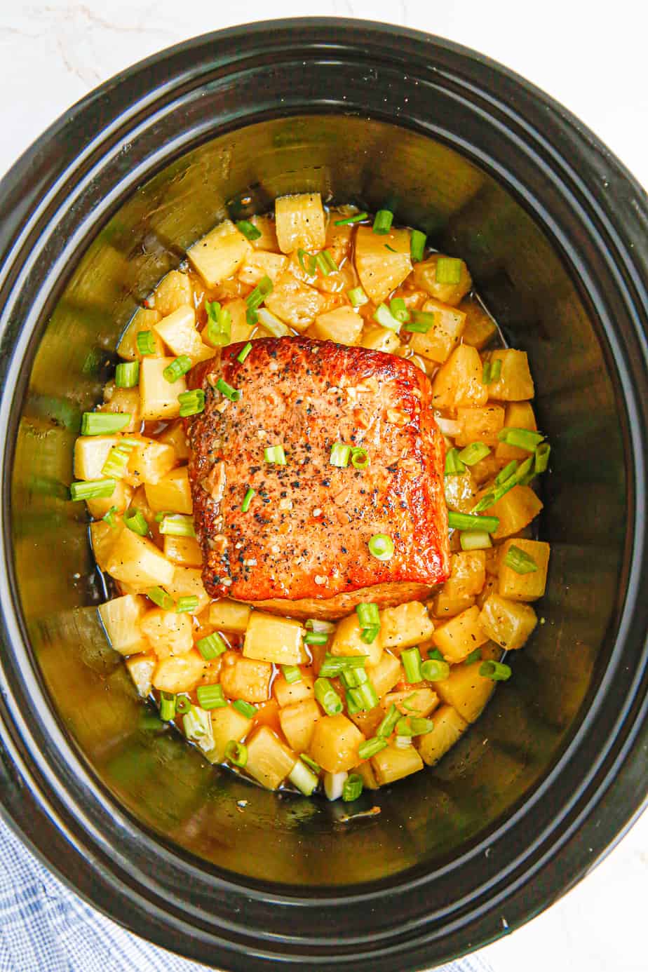 Cooked pork loin with pineapple in the slow cooker from overhead.