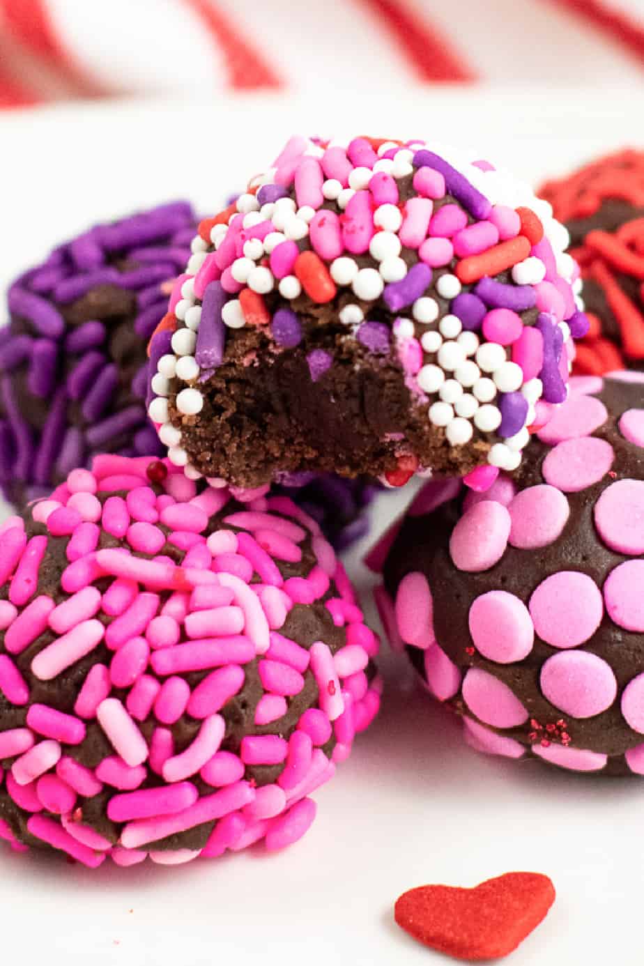 Up close of stack of brownie truffles in pink and red sprinkles with one truffle missing a bite