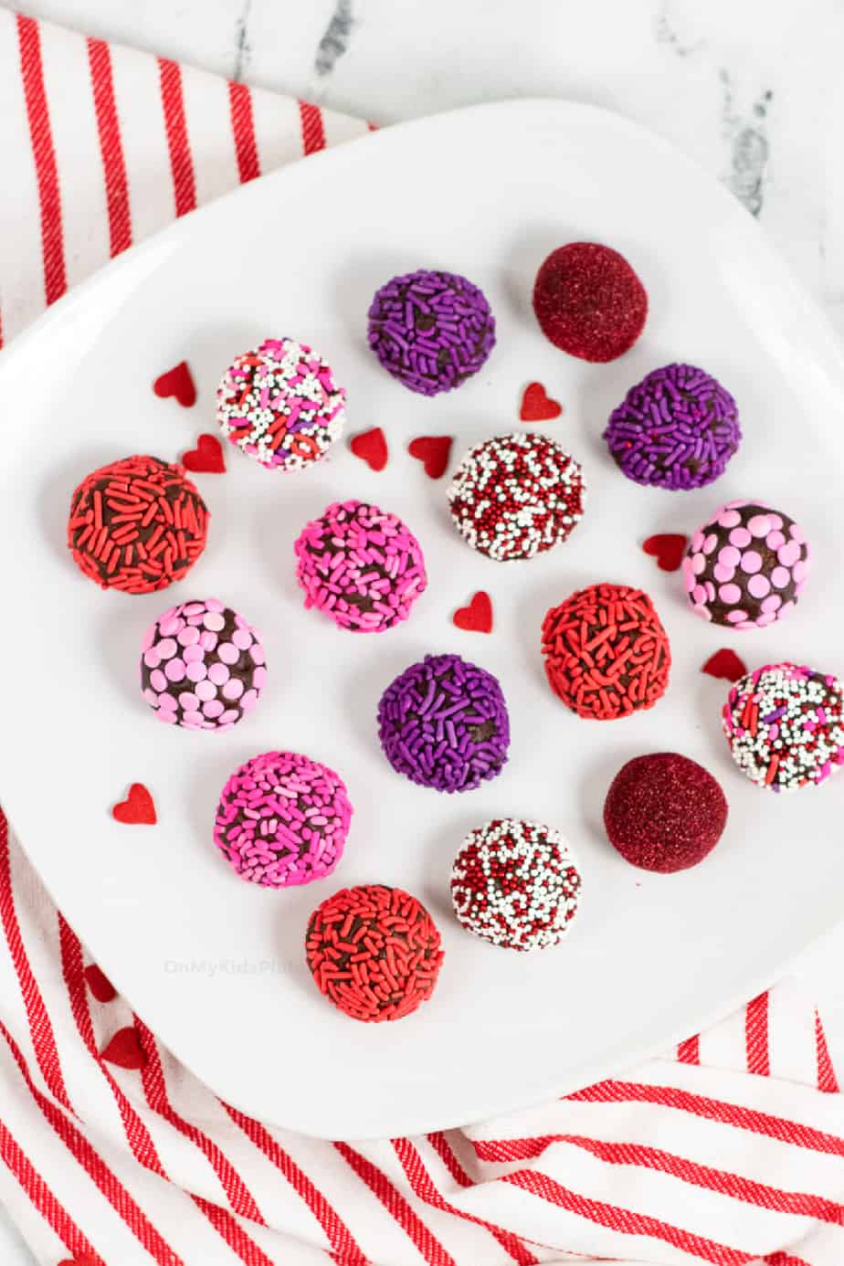 Overhead view of a platter of lined up brownie truffles covered in red, pink and purple sprinkles