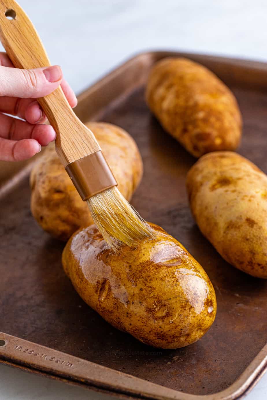 Brushing potatoes with oil