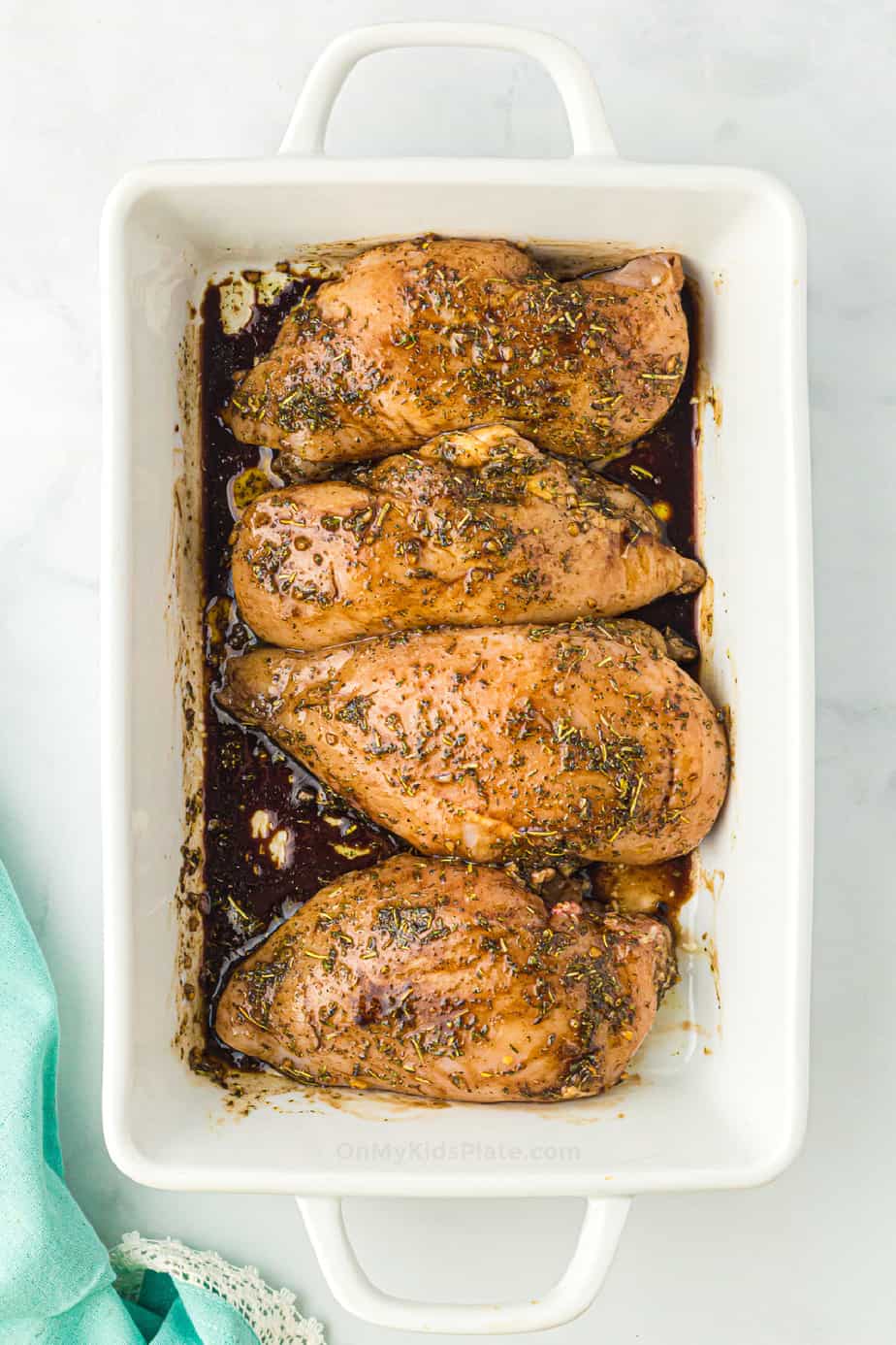 Baked chicken breasts in a balsamic sauce with herbs in a baking dish