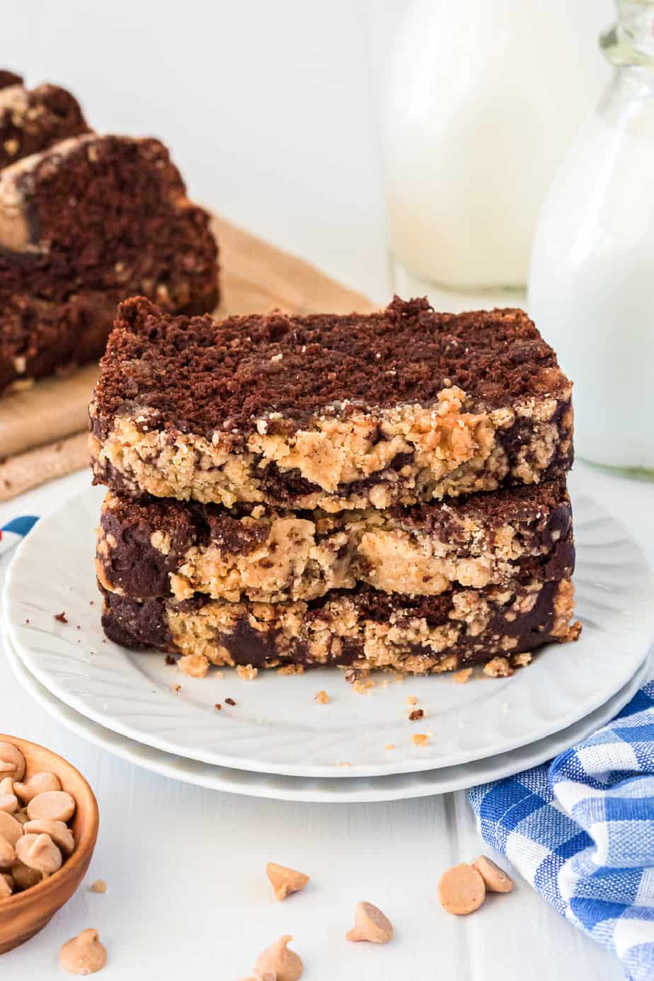 Stack of chocolate peanut butter bread slices on a plate on a table with milk and more slices behind