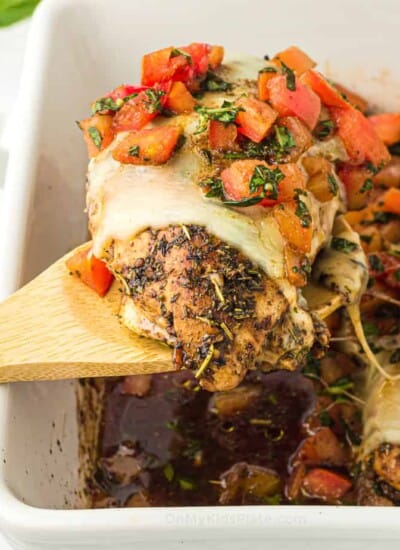 Bruschetta chicken being lifted from a pan with a spoon