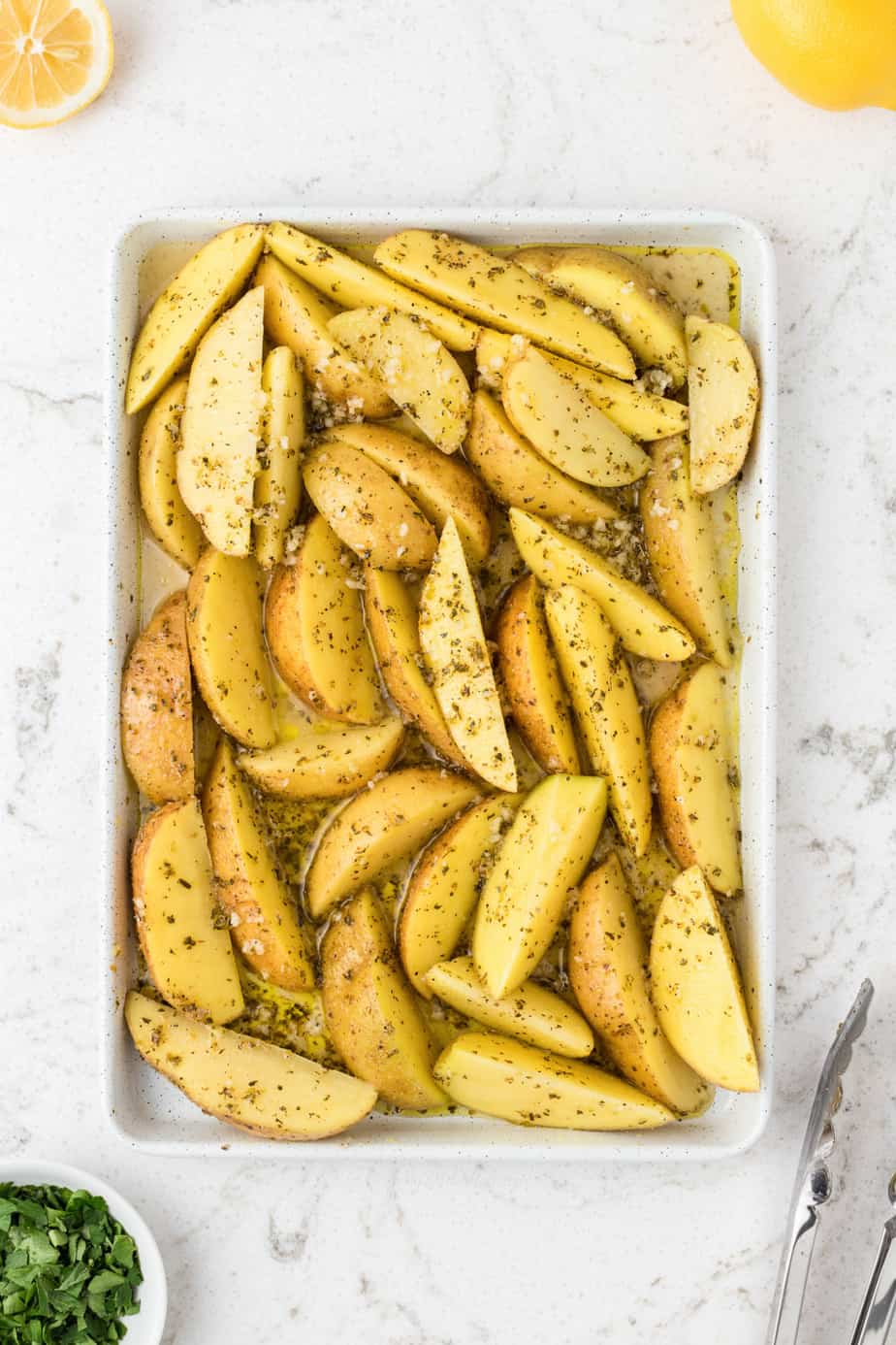 Potato wedges in a rimmed baking sheet seasoned before cooking
