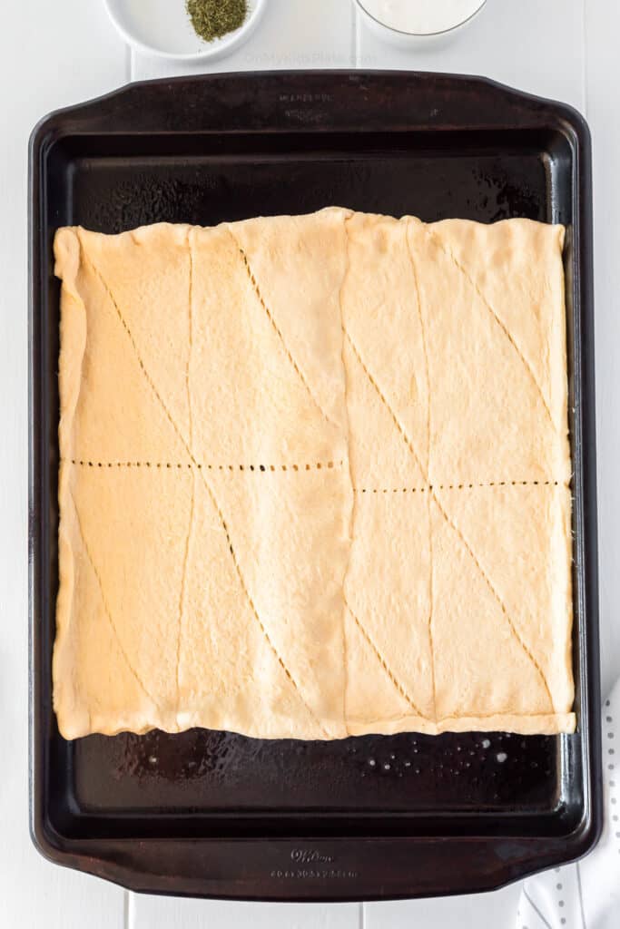 raw crescent dough stretched on a pan to form a crust