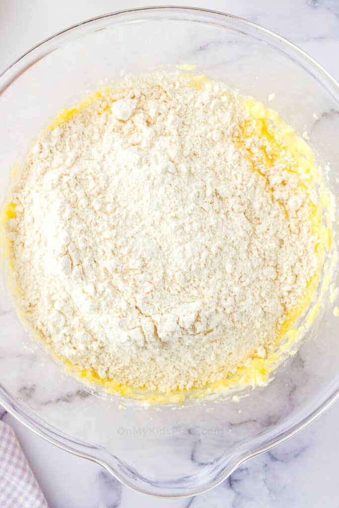Dry ingredients being mixed in a large mixing bowl with wet ingredients for cookie dough