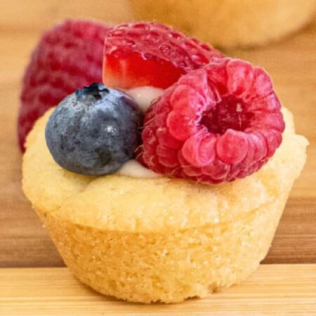 Close up of a cookie cup filled with cream cheese and topped with fruit on a platter