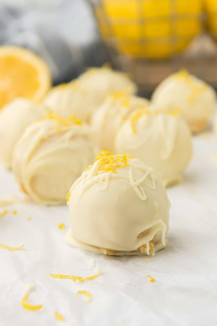 Lemon truffles from the side coated in white chocolate and topped with lemon zest