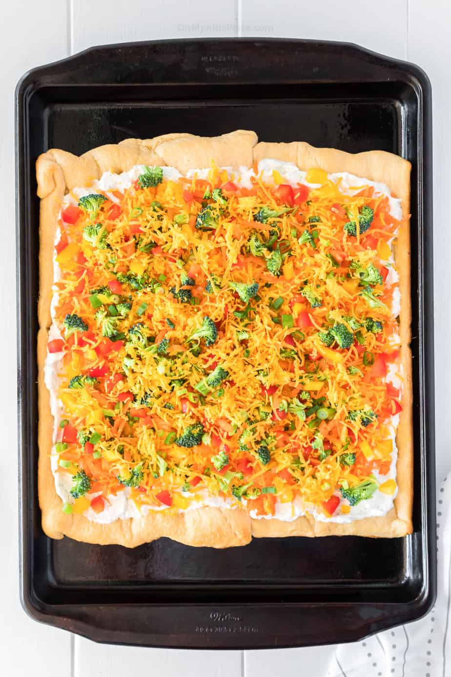 veggie pizza topped with veggies and cheese on the pan