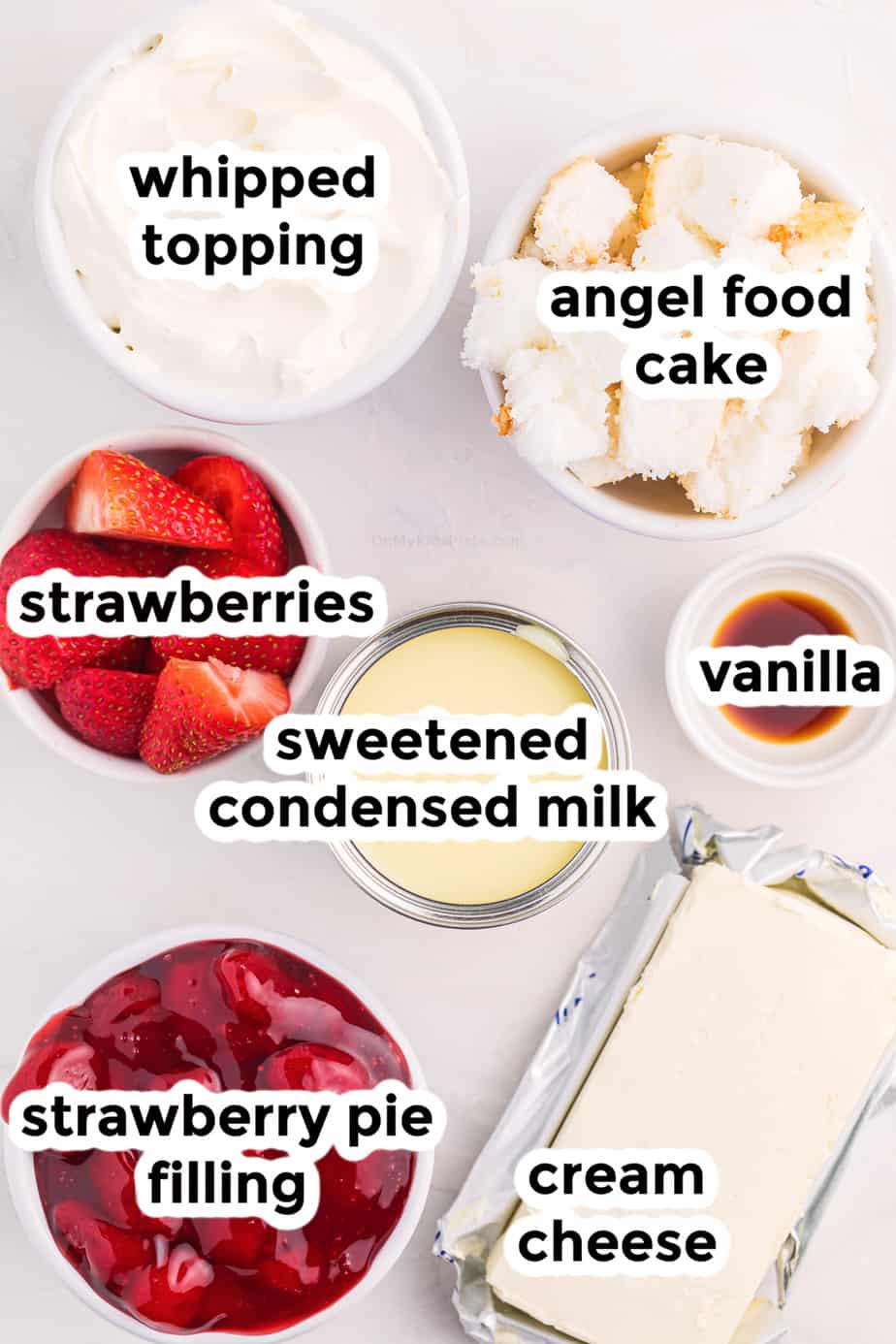 Ingredients for strawberry cheesecake dip in bowls with labels