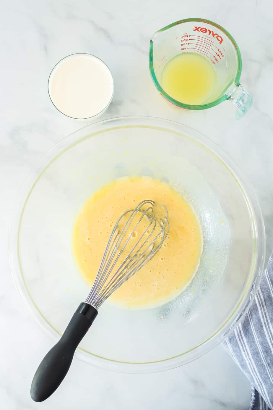 A large mixing bowl from above with wet ingredients being mixed with a whisk from overhead