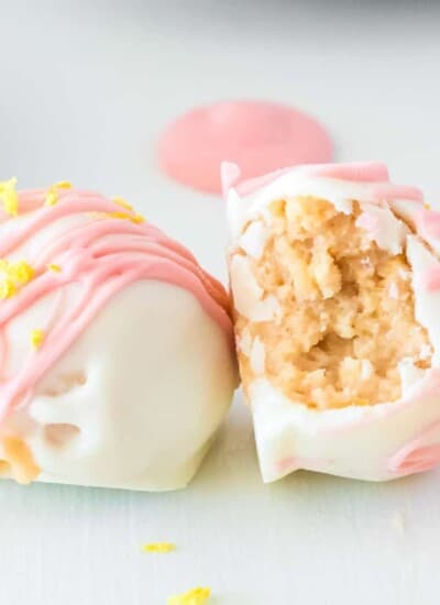 Two strawberry lemonade truffles side by side, one on it's side with a bite missing