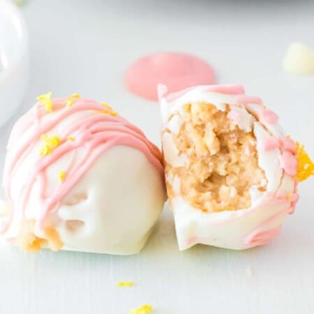 Two strawberry lemonade truffles side by side, one on it's side with a bite missing