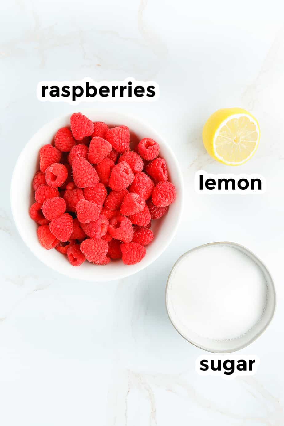 ingredients for raspberry jam in bowls on a counter with text labels