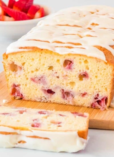 close up of the inside of a slice of strawberry bread topped with white glaze on a cutting board