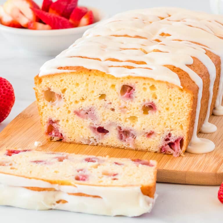 close up of the inside of a slice of strawberry bread topped with white glaze on a cutting board