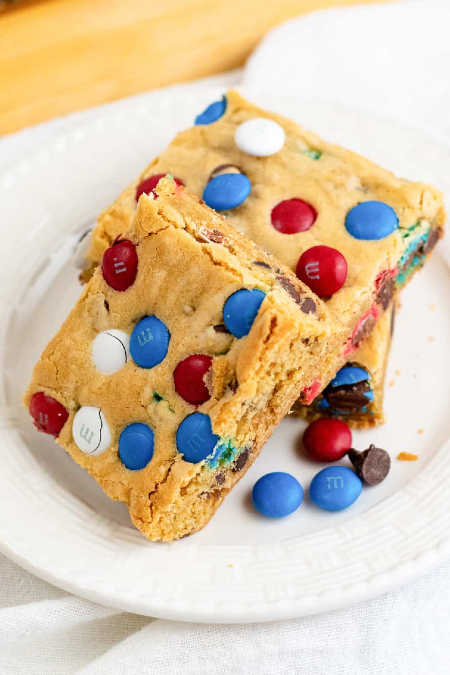 Cookie bars stacked on a plate from the side with red, white and blue MM candies on top of the bars.