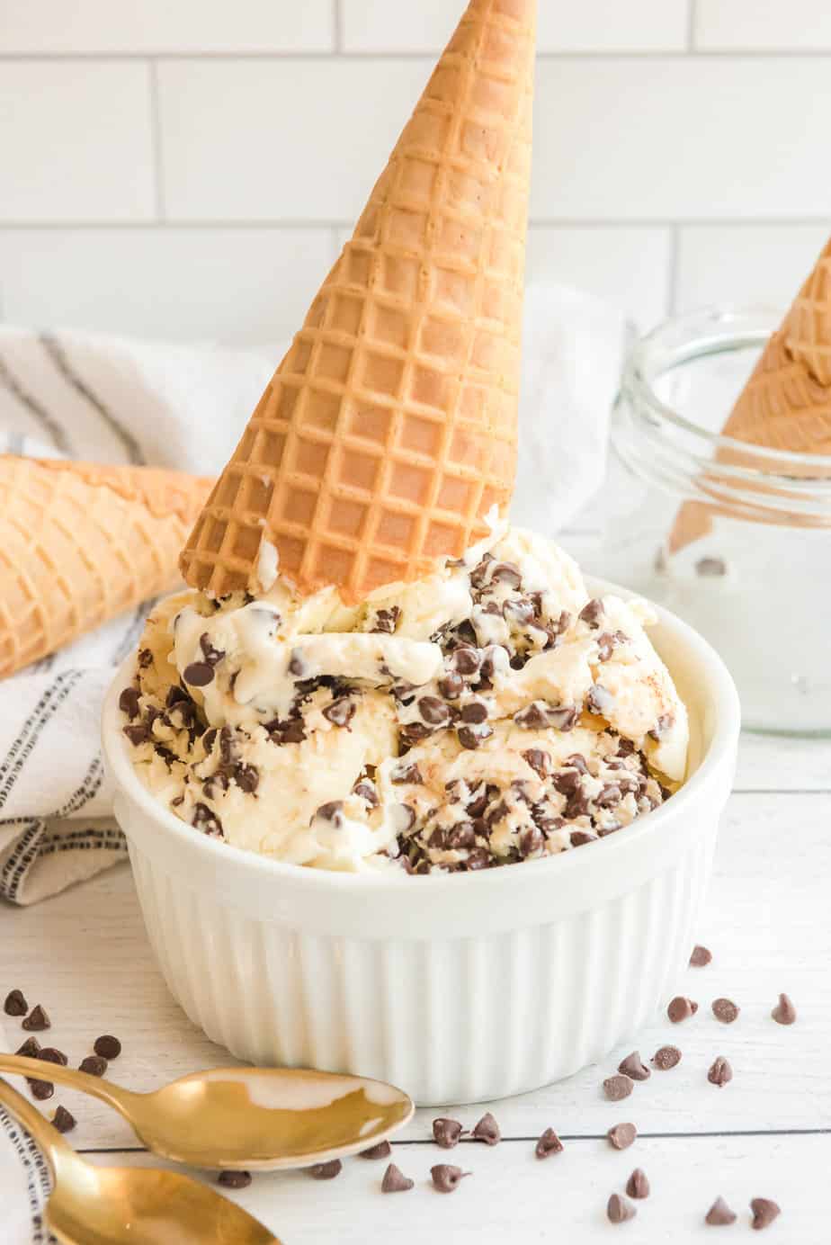 Chocolate chip ice cream in a bowl with a waffle cone placed on top upside down in the ice cream.