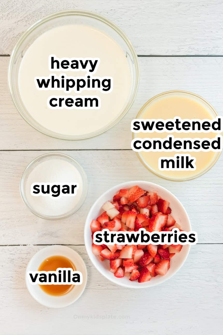 Ingredients for strawberry swirl ice cream in bowls from overhead with labels.