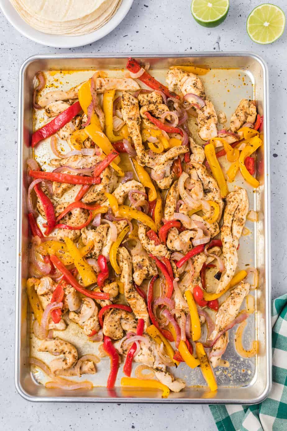 Juicy chicken fajitas with onions and bell peppers on a sheet pan cooked.