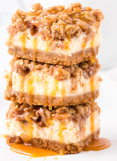 Three stacked apple caramel cheesecake bars with lots of gooey caramel from the side.