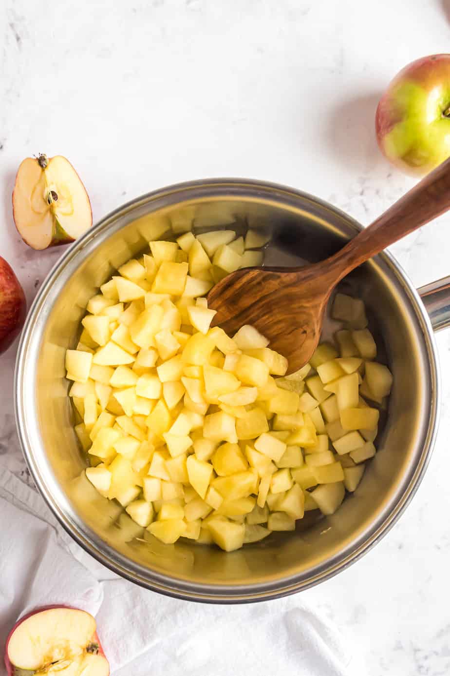 Cooked apples in a pan being stirred with a wooden spoon.