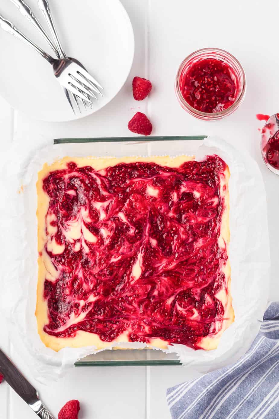 Raspberry cheesecake bars in a square pan on the counter after baking from overhead.