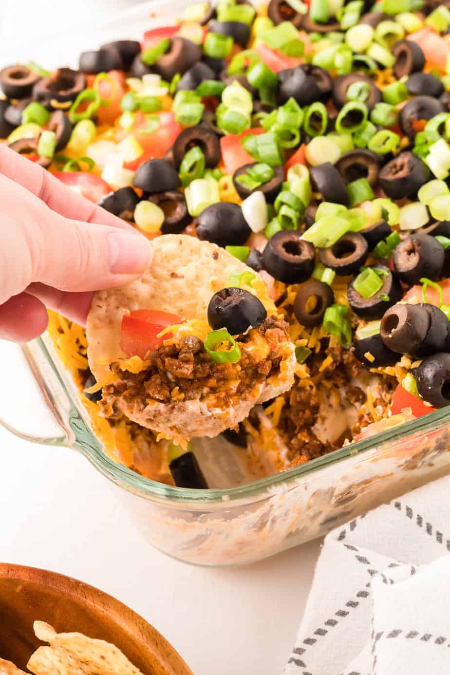 Dipping chip in taco dip with beef from the side.