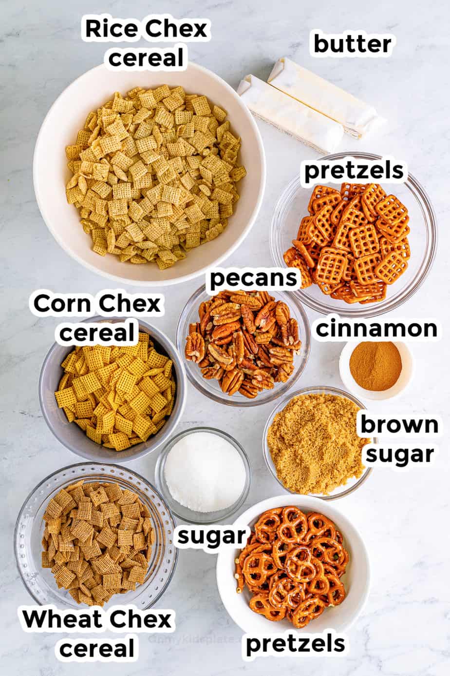 Ingredients in bowls from overhead with labels for cinnamon sugar chex mix.