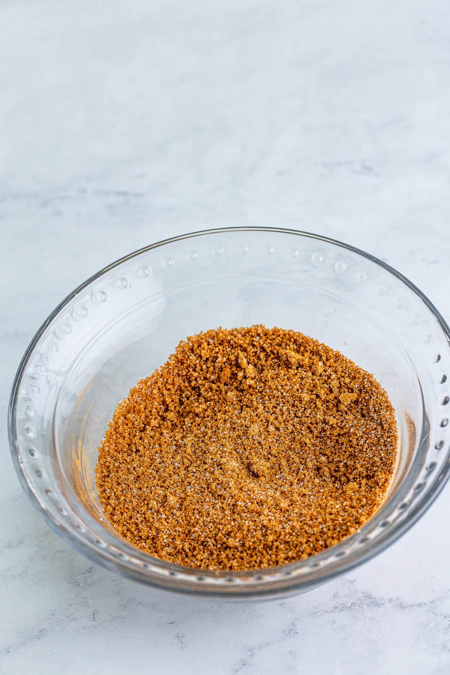 Crunch topping made of cinnamon and brown sugar mixed together in a small bowl from overhead on a counter.