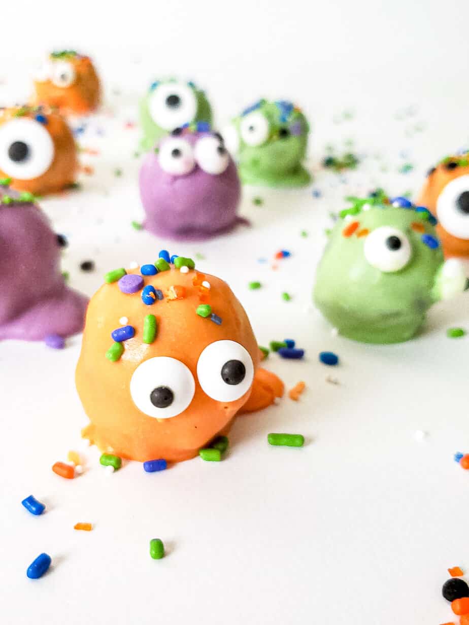 Monster oreo balls truffles in orange, purple and green from the side decorate with candy eyes and sprinkles.
