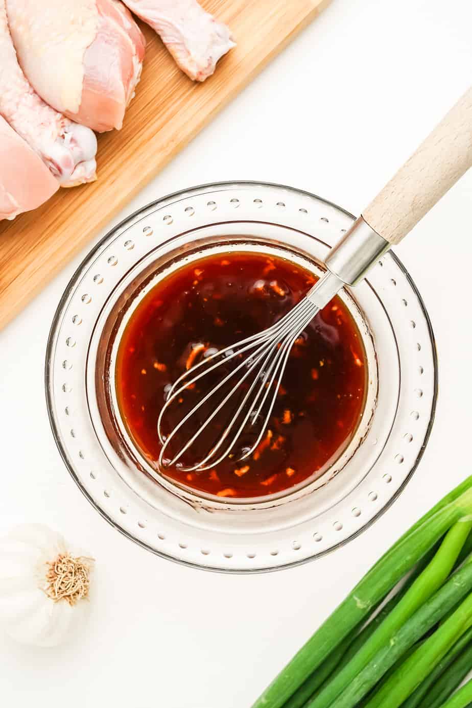 Mixing together sauce ingredients in a bowl from above with a whisk in the bowl.