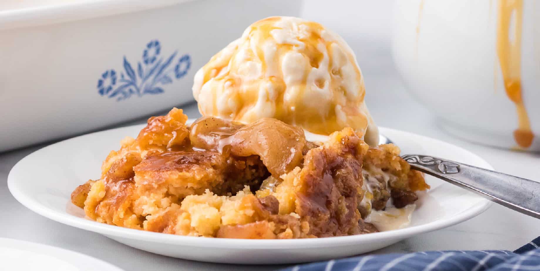 Wide view of caramel apple dump cake on a plate topped with ice cream from the side.