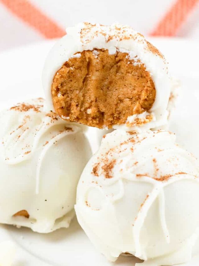 White chocolate pumpkin truffles on a plate with a bite taken out.