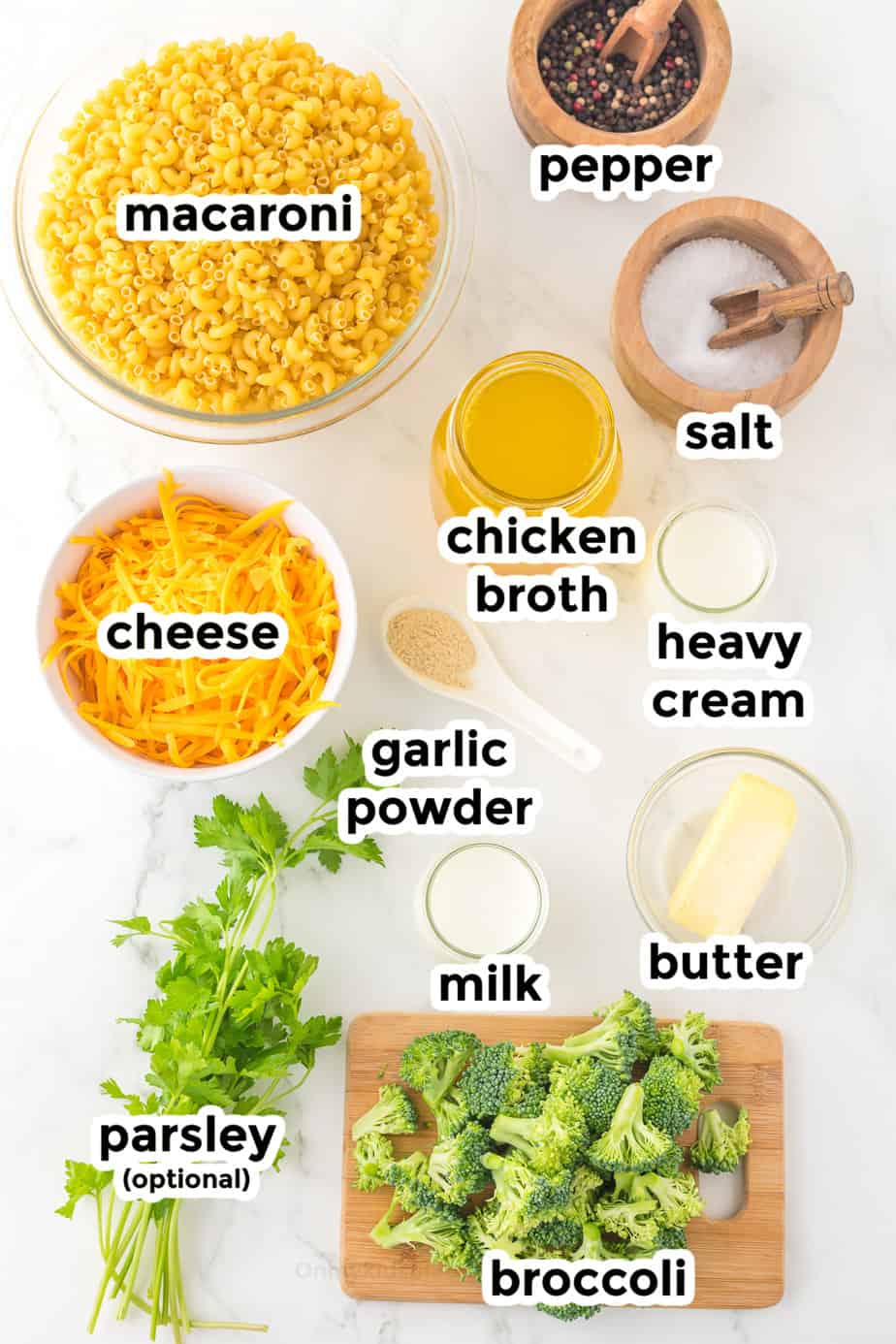 Ingredients for mac and cheese with broccoli in bowls from overhead on a counter with labels.