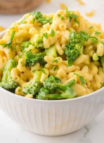 Mac and cheese with broccoli garnished with fresh parsley in a bowl from the side.
