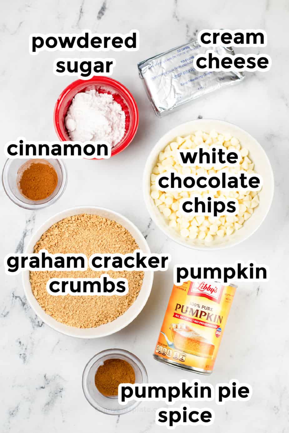 Ingredients in bowls on a counter from overhead for pumpkin cheesecake bites with labels.