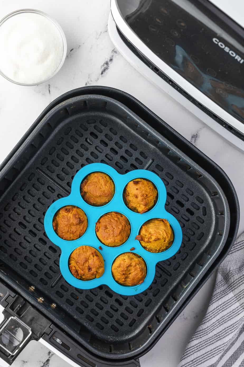 Pumpkin donut holes in a silicone pan in the bottom of a pull out air fryer drawer baked until golden brown from overhead on a kitchen counter.