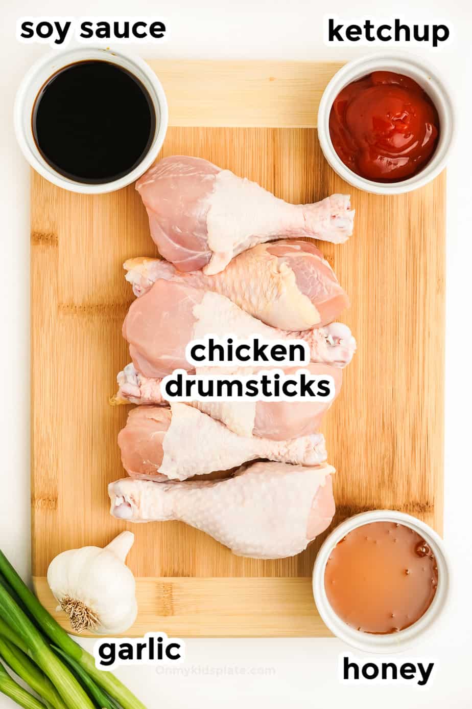 Ingredients for chicken drumsticks on a cutting board from overhead with labels.