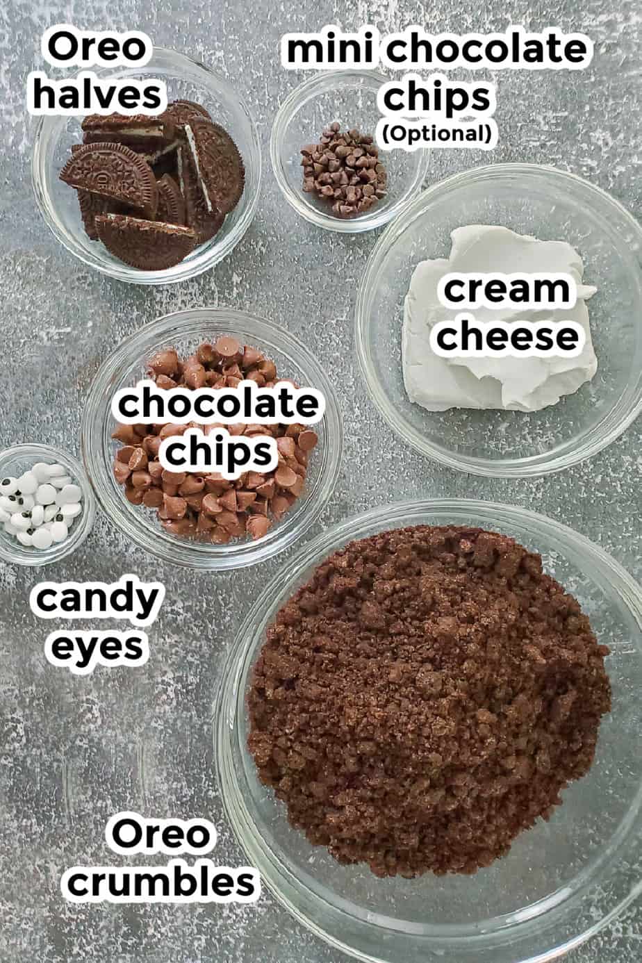 Ingredients for bat oreo balls in bowls from overhead with labels on a dark grey counter.