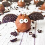 Close up of a chocolate covered Oreo ball on a counter decorated to look like a bat with cookies and chocolate.