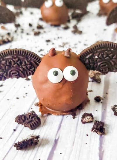 Close up of a chocolate covered Oreo ball on a counter decorated to look like a bat with cookies and chocolate.