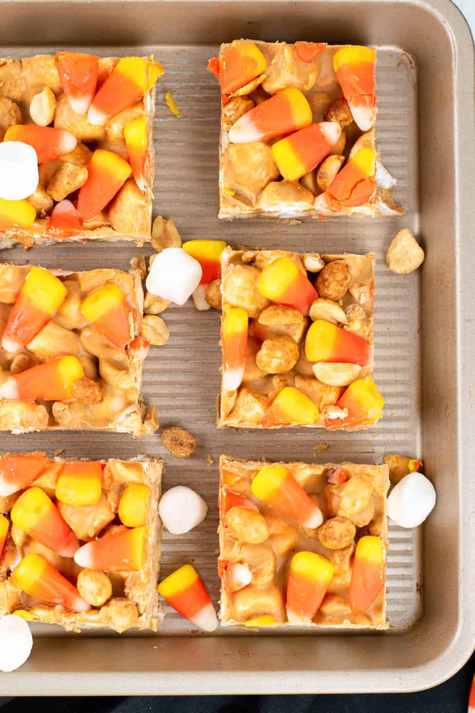 Close up of candy corn peanut butter marshmallow bars in slices spaced out on a pan from overhead.