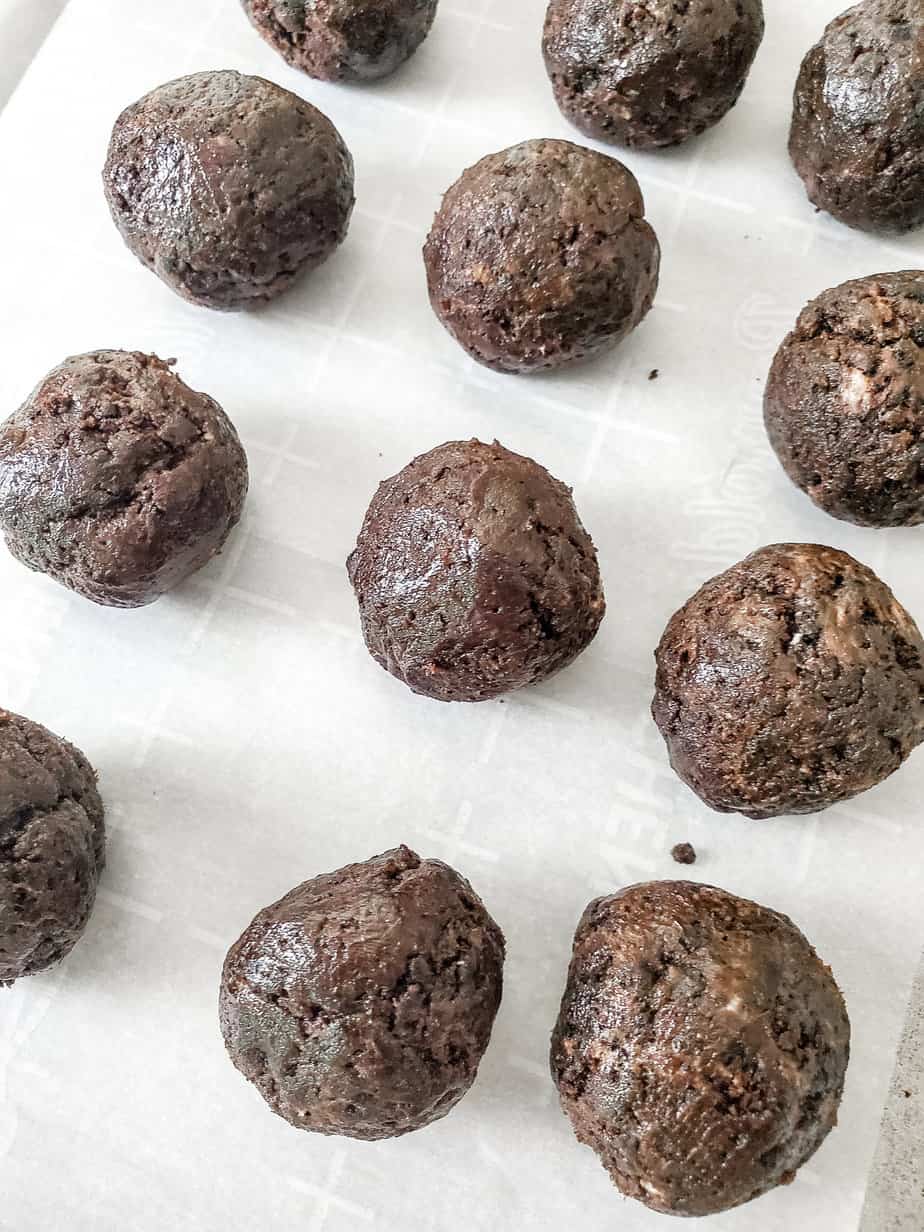 Oreo ball truffles close up from the side on parchment paper.