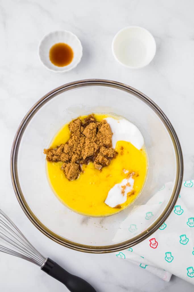 Mixing sugar, brown sugar, butter and wet ingredients in a large mixing bowl from above.