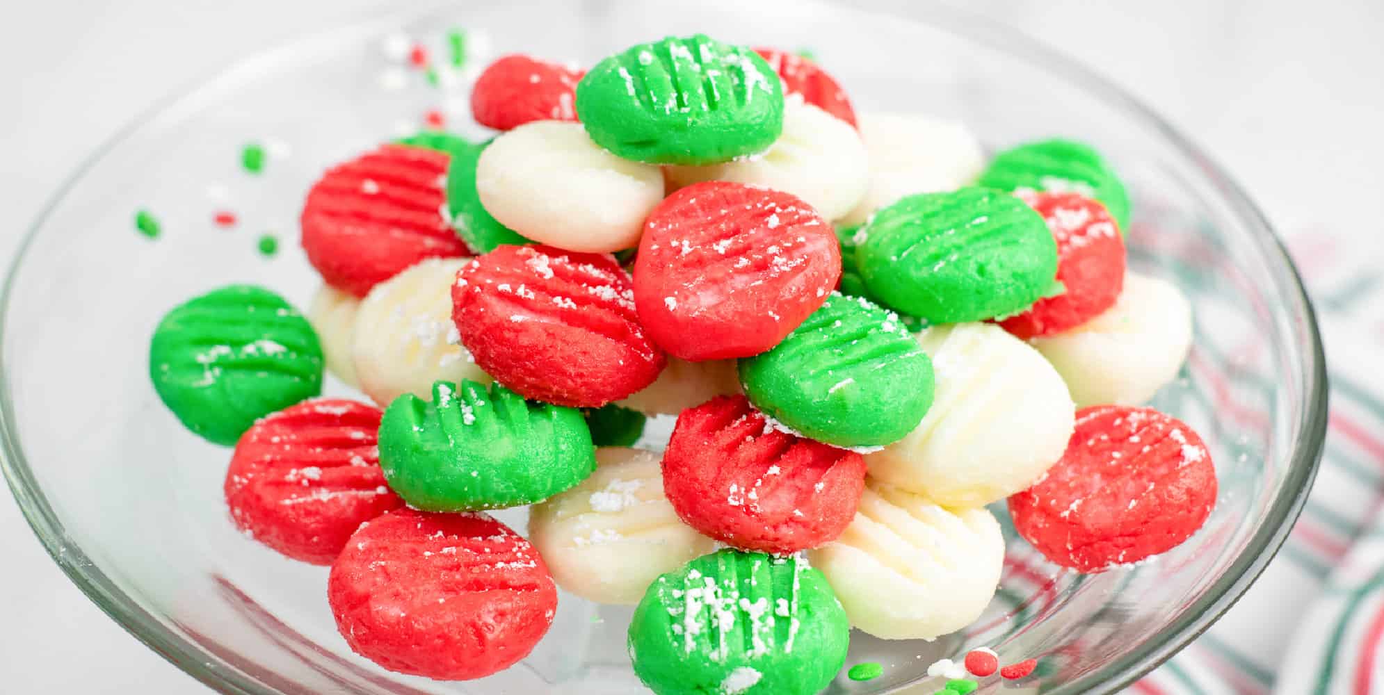 Cream cheese mints colored red, green and white piled high on a plate.