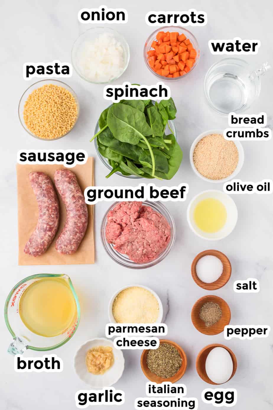 Ingredients for Italian wedding soup in bowls on a counter with text labels.