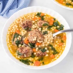 Italian wedding soup in a bowl on a counter from overhead full of meatballs, pasta and vegetables being lifted by a spoon.