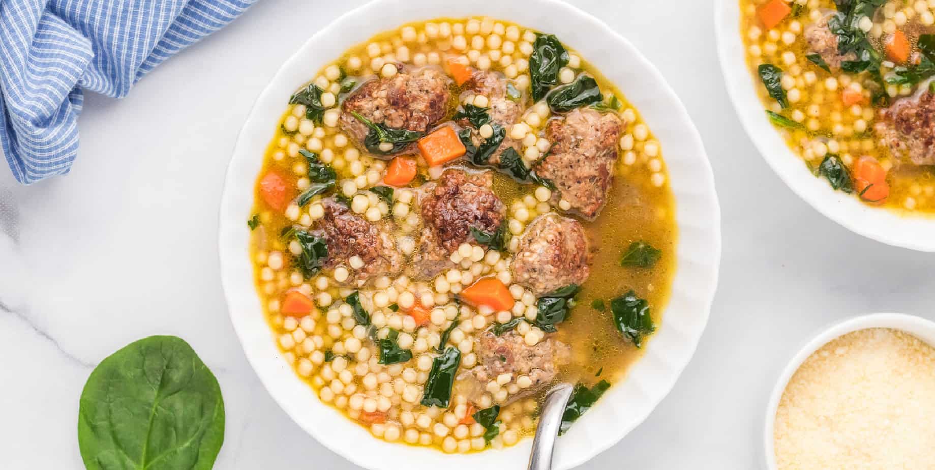 Italian wedding soup in a bowl on a counter from overhead wide view.