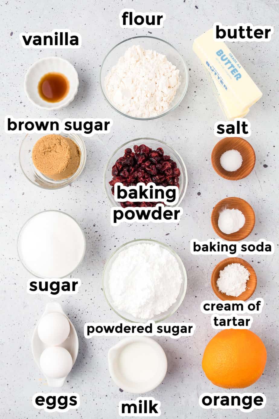 Ingredients for Orange Cranberry cookies on a counter in bowls with text labels.